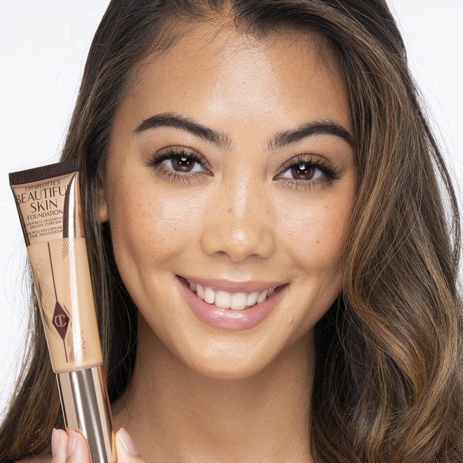 Medium-light-tone brunette model wearing glowy, skin-like foundation with a fresh, satin finish with a nude lipstick, and subtle eye makeup.