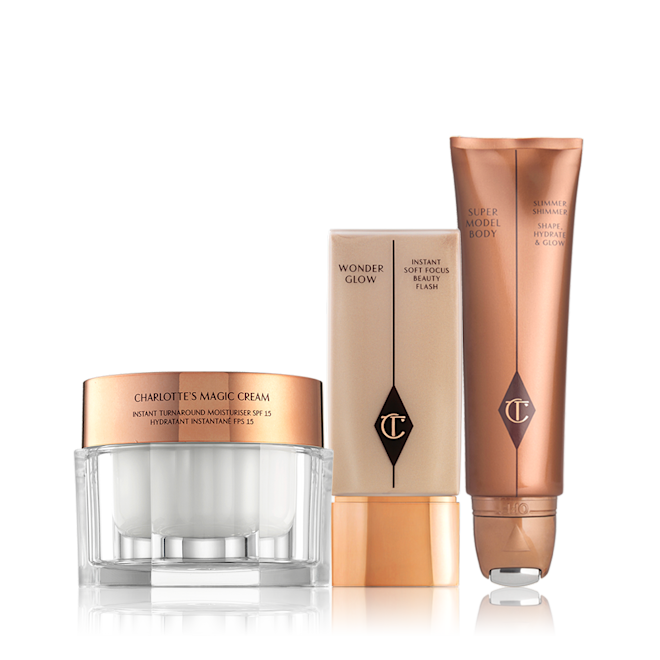 Magic Cream, Wonderglow, and Supermodel Body Bundle Face cream in a glass jar with a gold-coloured lid, foundation in a rectangular, transparent bottle with a square lid, and a body highlighter wand in a bronze-coloured tube.