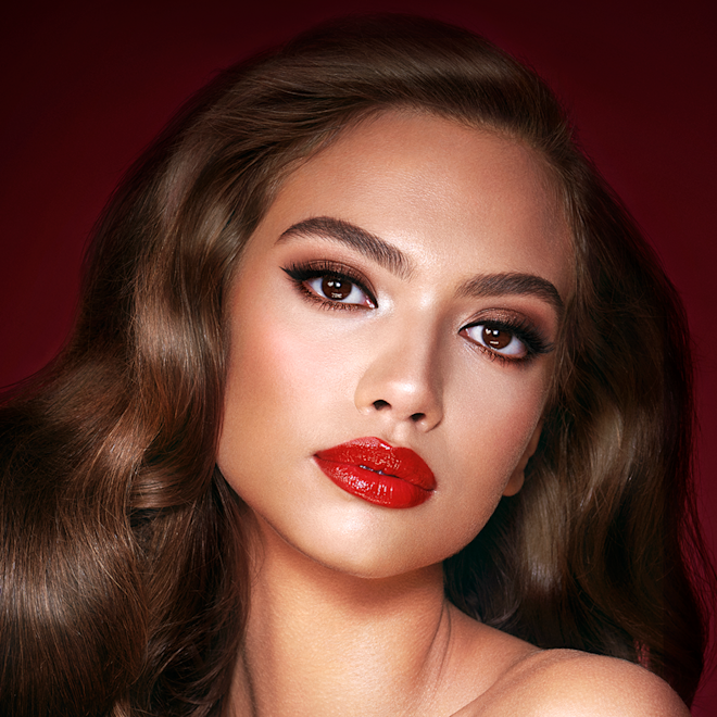 The Bombshell look on medium-dark tone model with brown eyes A medium-dark-tone model with brown eyes wearing shimmery bronze eye makeup with muted pink blush and glossy scarlet-red lips