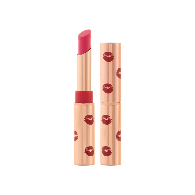 Two lipsticks, with and without lid, in a soft pink-red shade with gold-coloured tubes with red-coloured kiss print all over the tubes. 