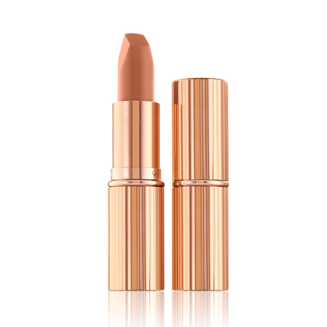 Two lipsticks, with and without lid, in a fresh, neutral nude peach matte shade, in sleek, gold-coloured tubes. 