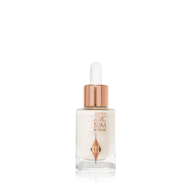A travel-size, pearlescent serum in a glass bottle with a white rose gold coloured dropper lid. 