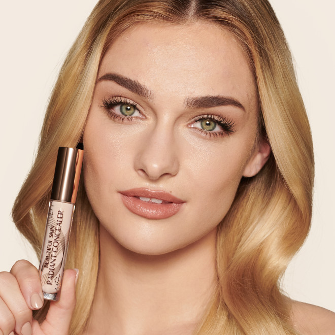 Fair-tone model with blue eyes wearing a radiant, concealer that brightens, covers blemishes, and makes her skin look fresh along with nude lip gloss and subtle eye makeup.