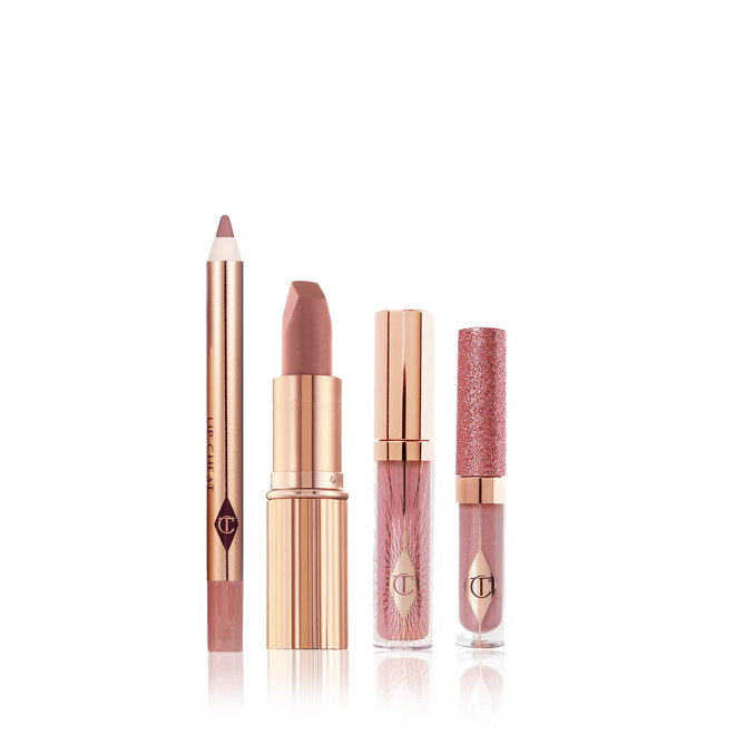 An open lip liner pencil, open nude pink matte lipstick, nude pink lip gloss in a glass tube with a gold-coloured lid, and shimmery nude pink lip gloss in a glass tube with a glittery lid. 
