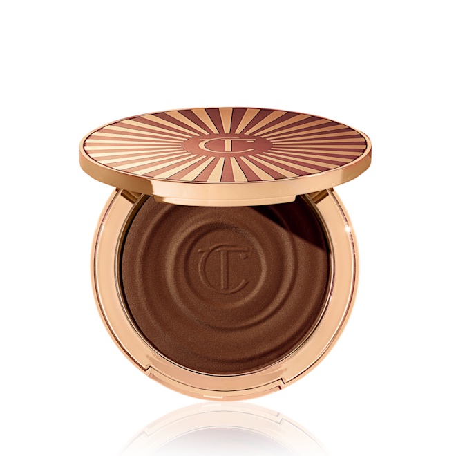 Beautiful Skin Sun-Kissed Glow Bronzer in Deep (molto scuro) aperto Bronzer in crema compatto aperto in una tonalità marrone-nero con confezione di colore oro.