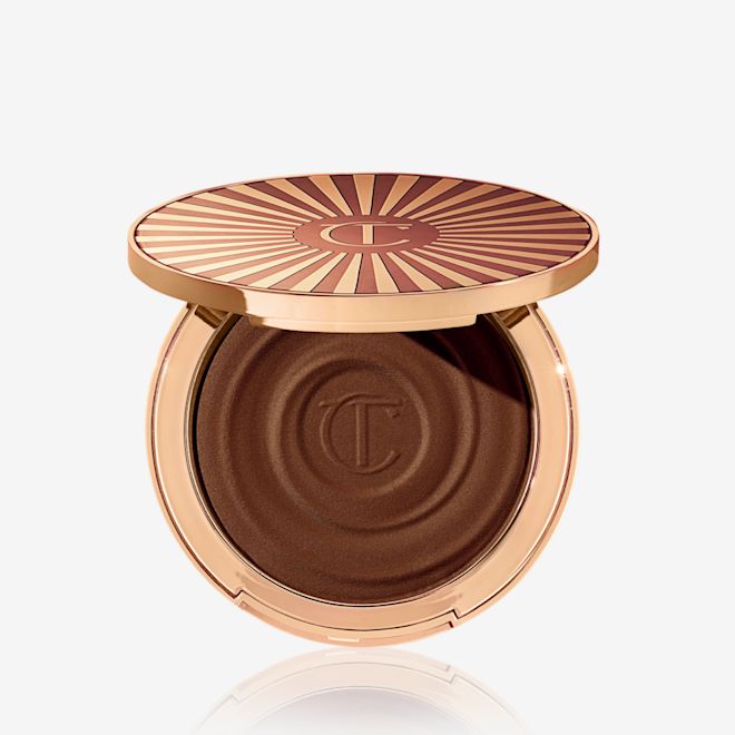 Beautiful Skin Sun-Kissed Glow Bronzer in Deep (molto scuro) aperto Bronzer in crema compatto aperto in una tonalità marrone-nero con confezione di colore oro.