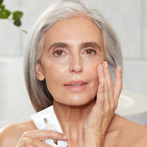 Modello maturo - Trattamento del viso Light-tone model with mature, flawless-looking skin washing off an exfoliating, chemical mask.