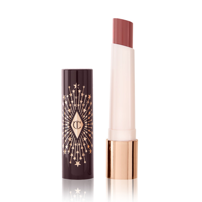 An open, moisturizing lipstick lip balm in a nude pink shade with a black and gold-coloured cover. 