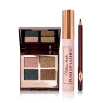 An open, mirrored-lid quad eyeshadow palette in shimmery pink, blue, and gold shades with a mascara with a nude pink tube and gold-coloured lid, and an eyeliner pencil in a black shade with a dark crimson body. 