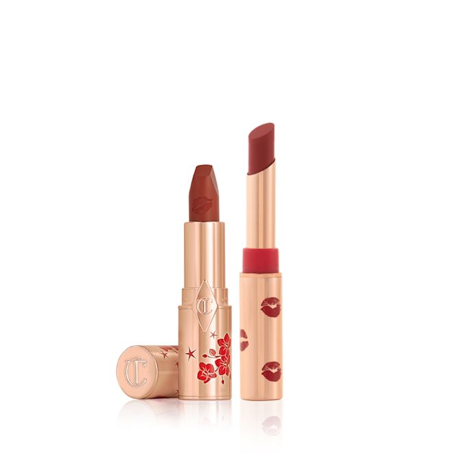 Lucky Lips duo A matte burnt-orange red lipstick in gold-coloured packaging with cherry blossoms illustrated on the tube for the Lunar New Year, along with its lid next to it and a berry red lipstick in a gold-coloured tube with lipstick kiss prints all over the tube.