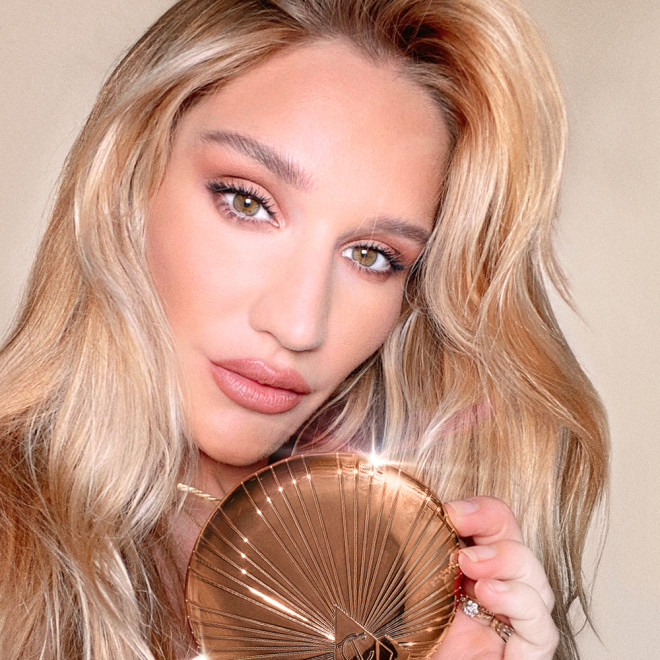Sofia Tilbury holding a bronzer compact in dark golden packaging with a starburst pattern on the outside. 