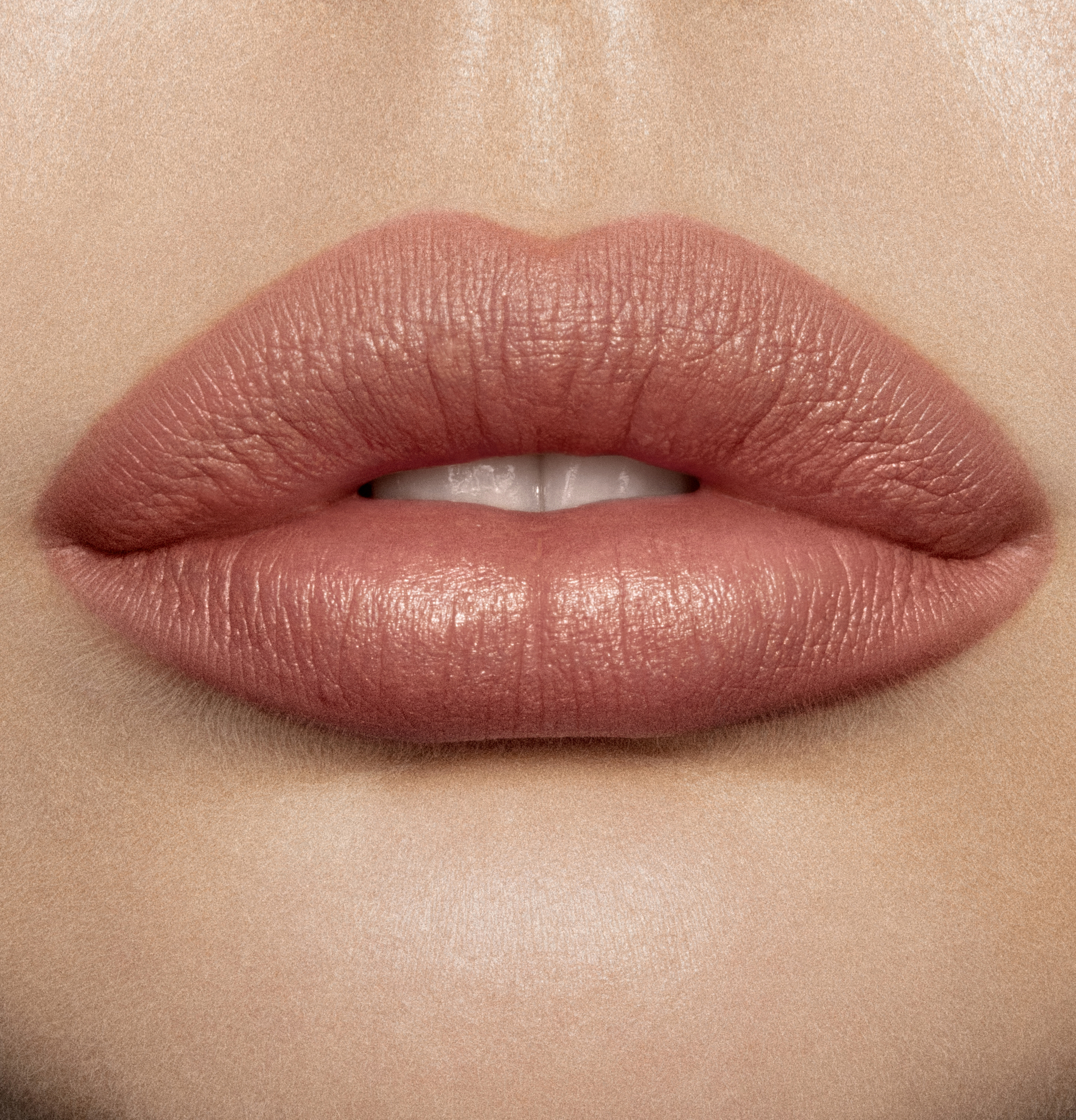 Lips close-up of a model wearing a mid-toned muted nude-rose matte lipstick.