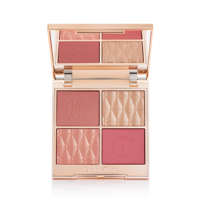 An open, face palette with matte and shimmery eyeshadows, blushes and highlighters in shades of pink and gold with a mirrored lid.