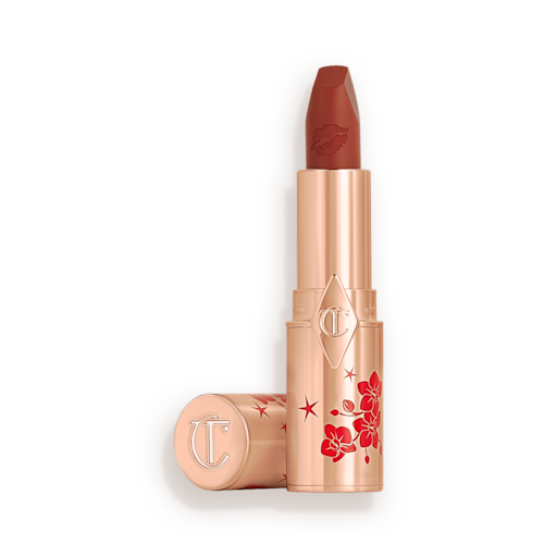 Matte Revolution lipstick in Blossom Red open A matte burnt-orange red lipstick in gold-coloured packaging with cherry blossoms illustrated on the tube for the Lunar New Year, along with its lid next to it.