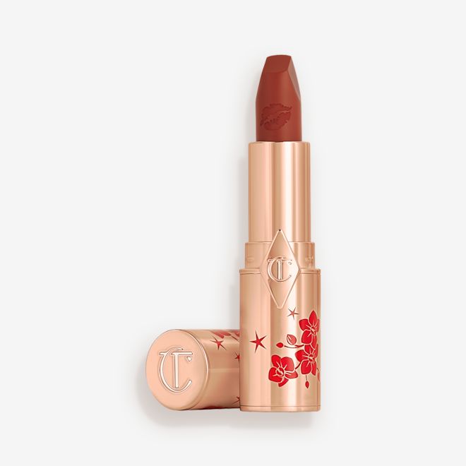 Matte Revolution lipstick in Blossom Red open A matte burnt-orange red lipstick in gold-coloured packaging with cherry blossoms illustrated on the tube for the Lunar New Year, along with its lid next to it.