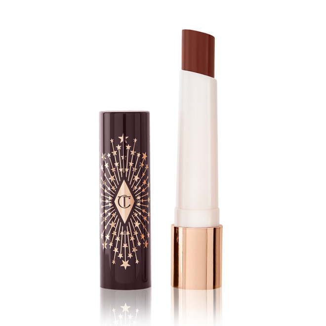 An open lipstick lip balm in a sheer soft brown shade, in white and gold tube with a black-coloured lid with gold sparkles all over it.