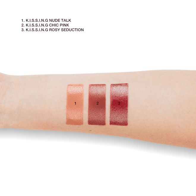 K.I.S.S.I.N.G lipstick swatches of fair-tone arm Fair skin model arm close-up showing the swatches of three satin finish lipsticks in shades of nude peach, medium pink, and deep rose pink.