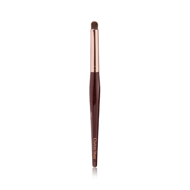 An eyeshadow smudging brush with soft bristles and rose gold and dark crimson handle. 