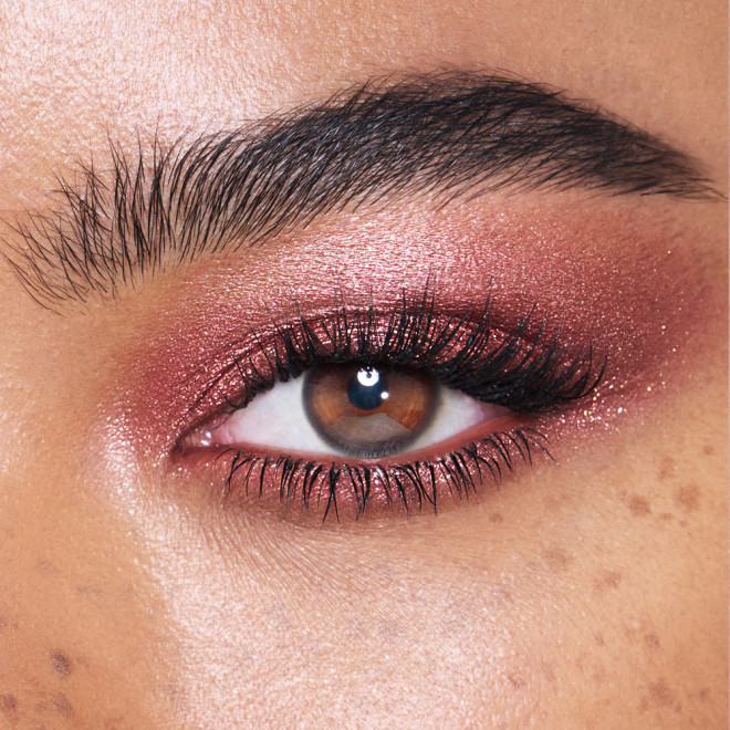 Close-up of a model with brown eyes wearing iridescent rustic red eyeshadow with very fine shimmer. 