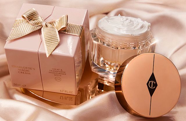 Charlotte's Magic Cream with gift box Pearly-white face cream in a glass jar with a gold-coloured lid and a pink-beige-coloured packaging box with a gold-coloured ribbon wrapped around it.