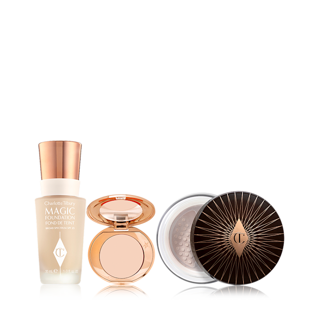 Charlotte's Magic Complexion Secrets displayed Foundation in a glass bottle with a gold-coloured lid, colour corrector compact in a light shade with a mirrored-lid, and loose setting powder with a black and gold-coloured lid.