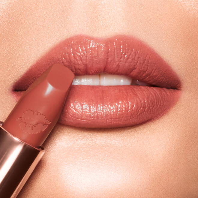 Light-tone model applying a rusty rose-coloured lipstick with a satin-finish. 