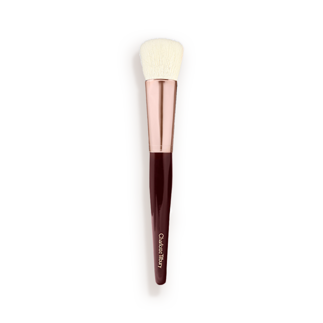 Magic Complexion Brush A face blending brush with cream-coloured bristles with a rose-gold and dark crimson handle.