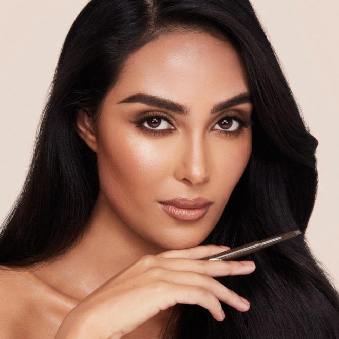 Medium-tone model with brown eyes and brows lined, shaped, and filled with a black-brown-coloured eyebrow pencil.