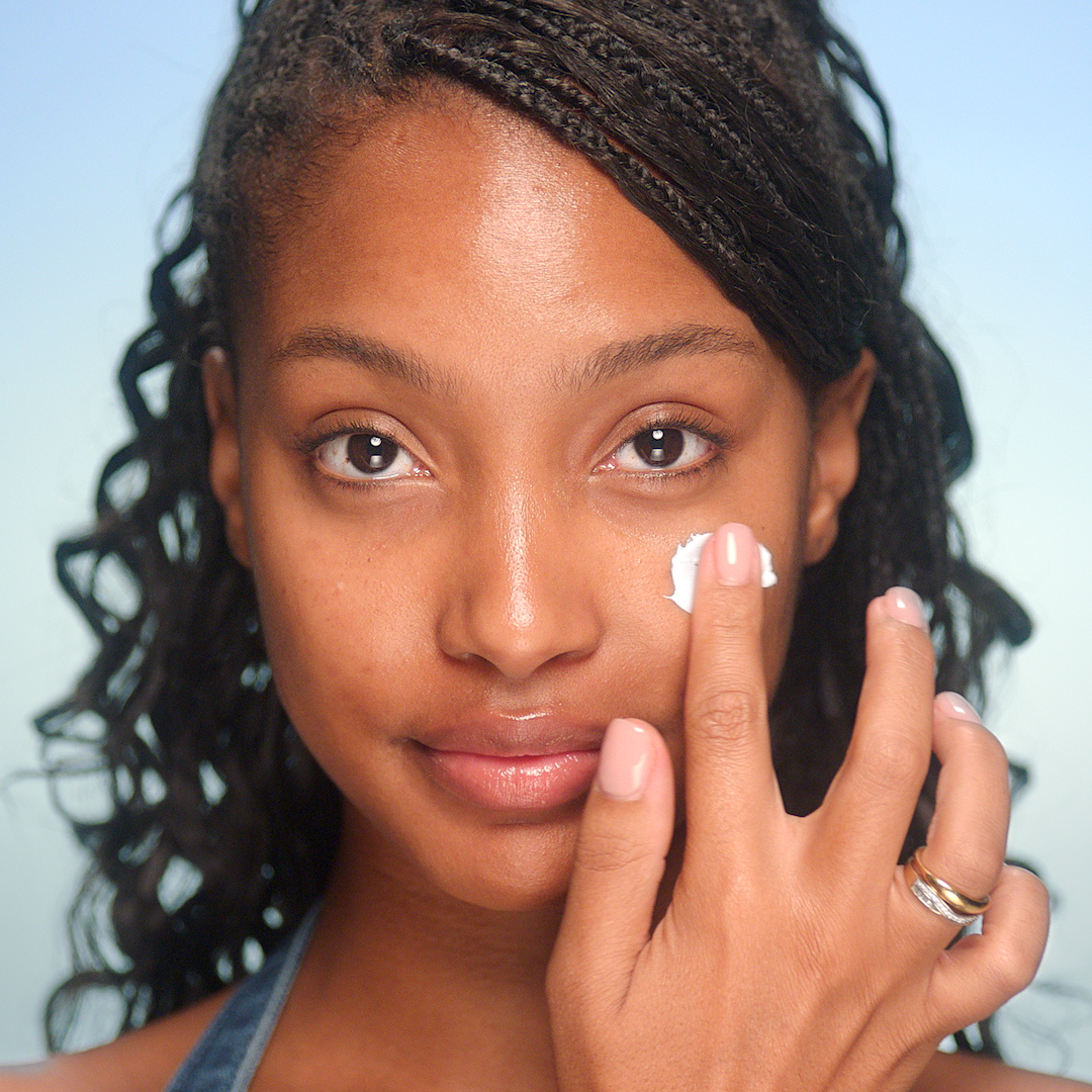2000s makeup step 1 - apply moisturiser Model with bare face having moisturiser applied to her face.
