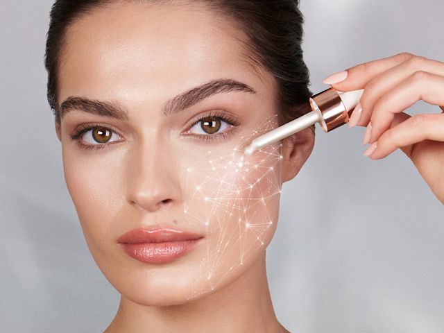 Magic Serum Crystal Elixir on fair tone model A fair-tone brunette model applying a pearly-white, glowy face serum with a dropper.