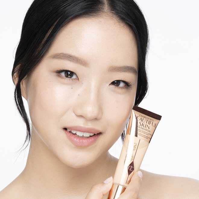Fair-tone brunette model wearing glowy, skin-like foundation with a satin finish with nude lipstick and subtle eye makeup.