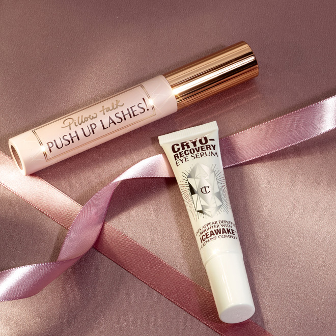 Black mascara in a sheer pink-coloured tube with text on it that reads, 'Pillow Talk Push up lashes!' and a gold-coloured lid with an eye serum in a white-coloured tube.