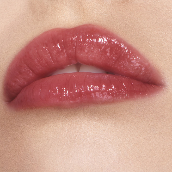 Lips close-up of a fair-tone model wearing a high-shine lip gloss in a berry-oink shade.