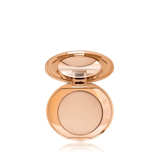 An open, mirrored-lid, mini, pressed powder compact in a light beige shade. 