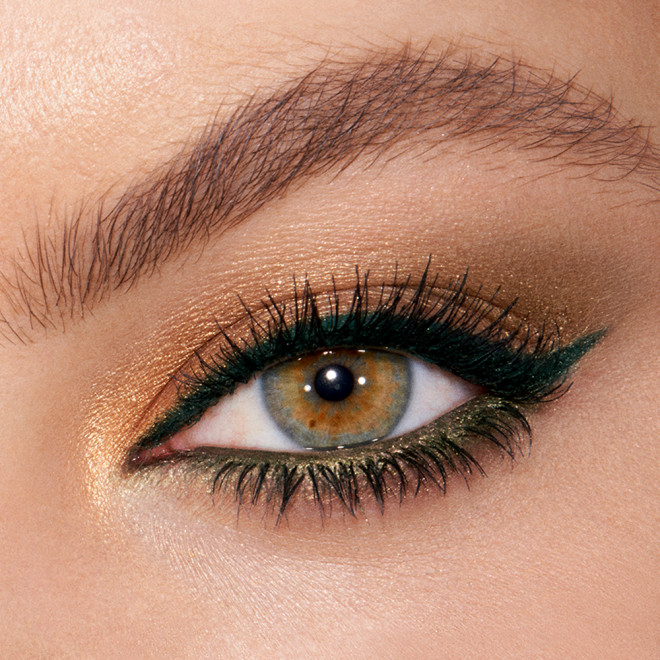 Close-up of shimmery, golden and green eye makeup on a fair-tone model with hazel eyes.