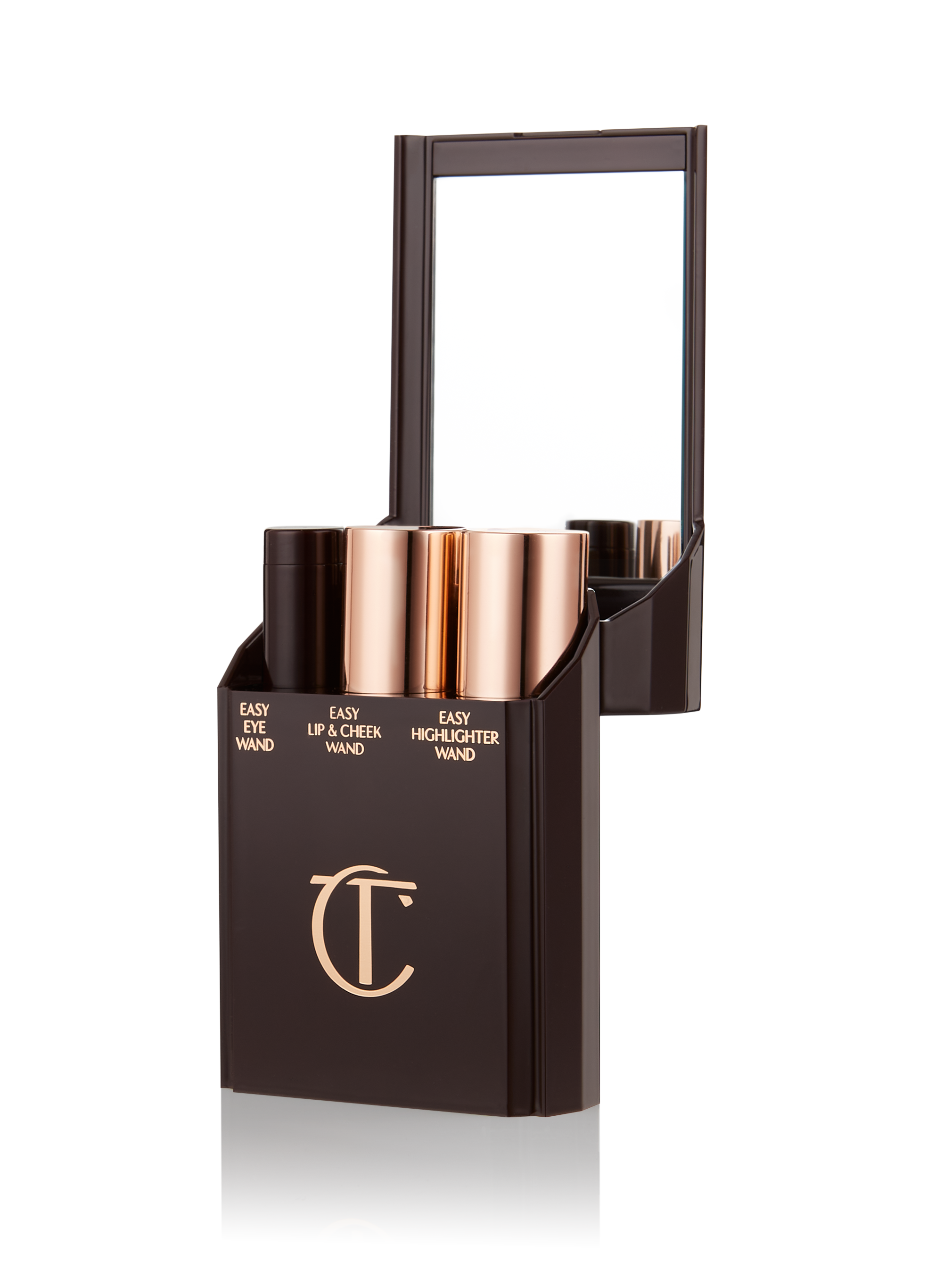 Quick & Easy Instant 5 Minute case open An open, black-brown-coloured portable makeup case with a mirrored lid, with three product places, which are filled with an eyeshadow stick, lip and cheek stick, and highlighter stick.