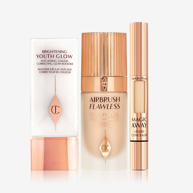 Brightening Youth Glow, Airbrush Flawless Foundation, and Magic Away Concealer displayed A primer in white and rose gold packaging with a foundation in a frosted glass bottle and rose-gold lid, and a concealer in rose-gold packaging with a small window on the tube to see the concealer shade.