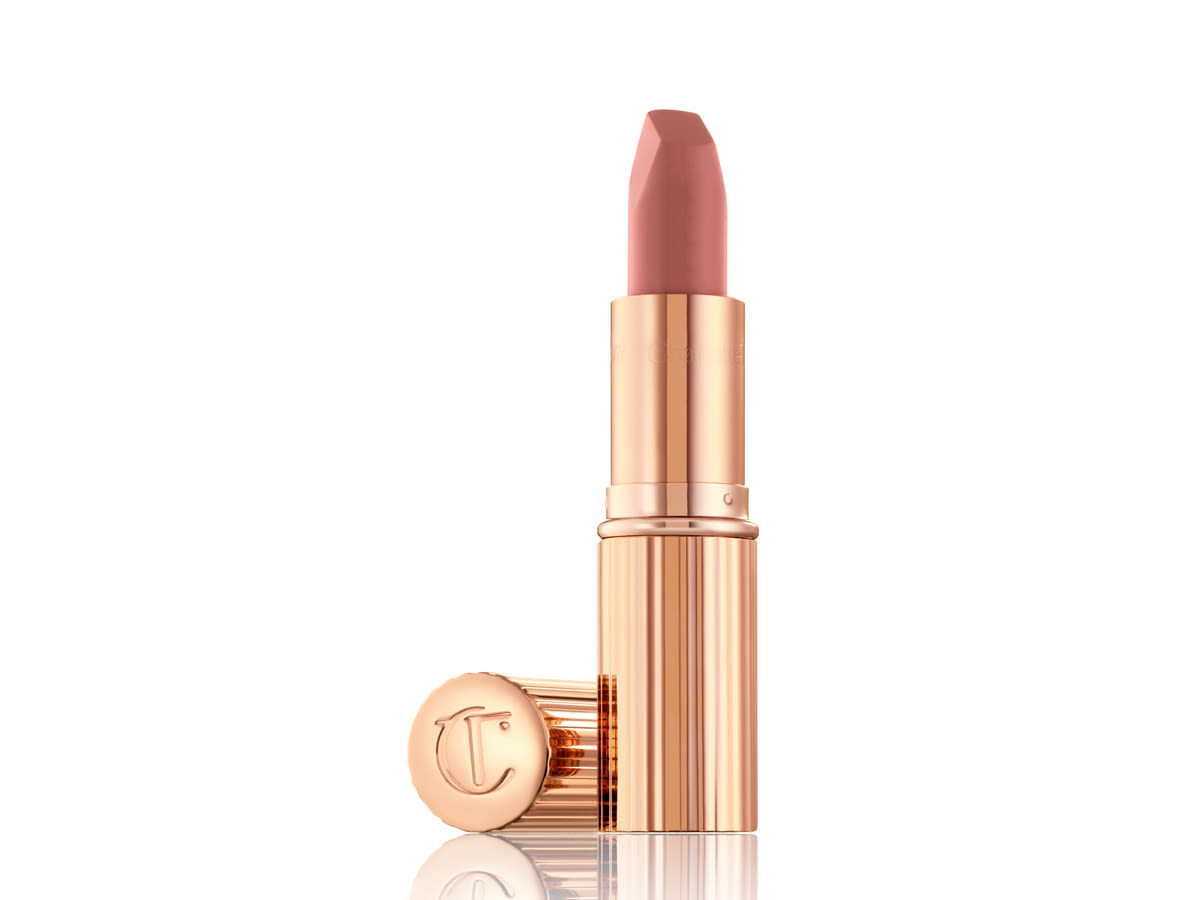 Matte Revolution in Pillow Talk Original without lid An open matte lipstick in a nude pink shade in a golden-coloured tube with the lid next to it.
