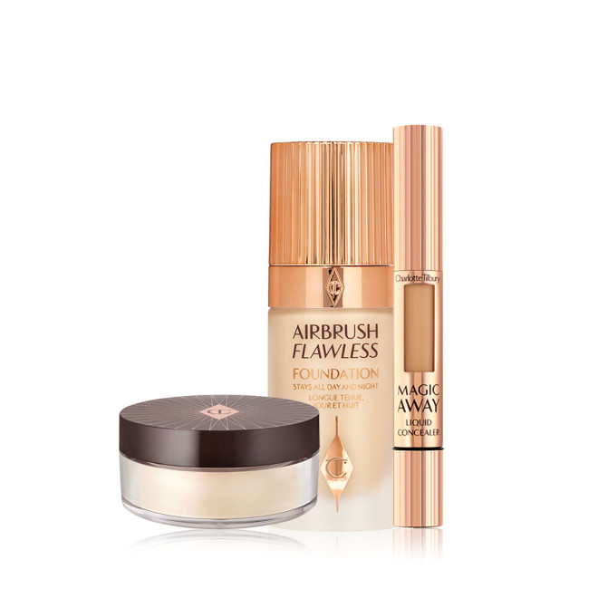 Creamy liquid concealer in a sleek gold-coloured tube with a soft sponge end for application, foundation in a frosted glass bottle with a gold-coloured lid, and loose powder in a light yellow shade in a transparent pot with a black-brown-coloured lid.