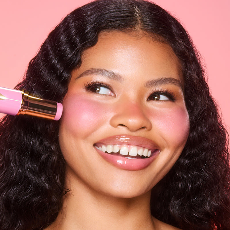 Beach Sticks model shot Model wearing Unreal Blush Healthy Glow Stick cream blush stick in Peachy Glow on nose