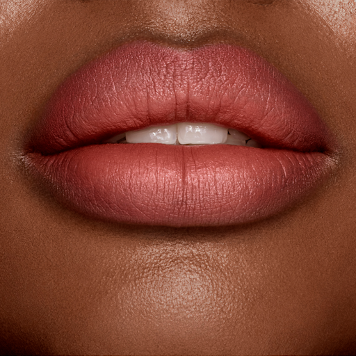 Look of Love Lipstick in Mrs Kisses deep tone model lips close-up Lips close-up of a deep-tone model wearing a matte, golden peachy-pink lipstick.