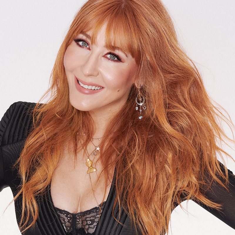 Charlotte Tilbury wearing nude-pink glowy makeup with minimal jewellery and a black dress. 