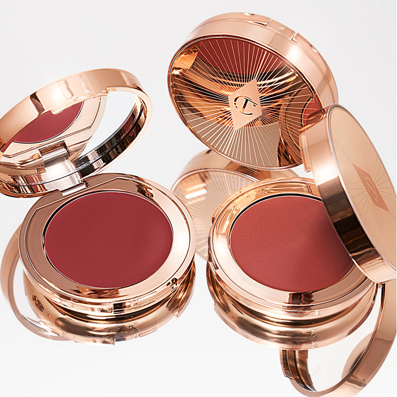 A collection of lip and cheek cream tints in berry-pink and peachy-pink shades in gold-coloured compacts.