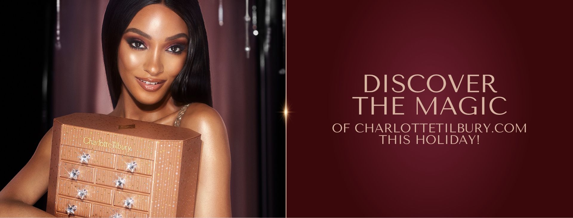 Charlotte's Instant Eye Palette Advent Calendar held by deep-tone model Banner with a golden-coloured chest of drawers filled with skincare and makeup items along with a deep-tone model carrying the chest.