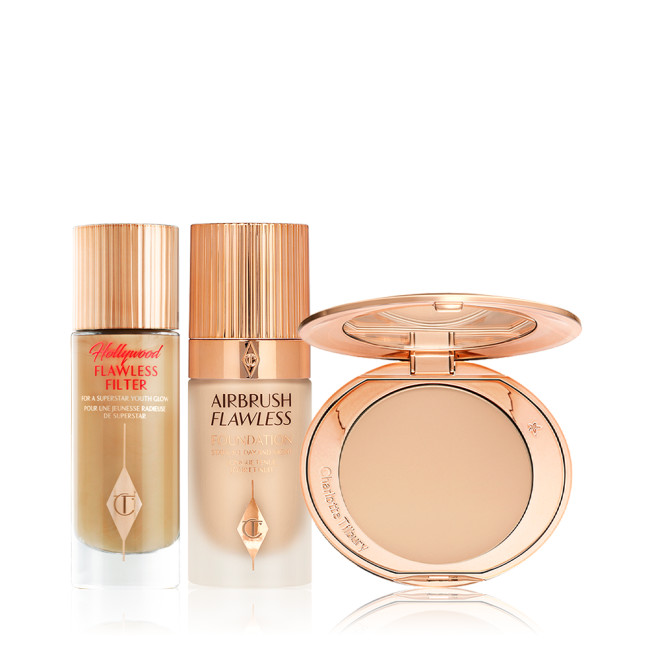 Glowy primer in a glass bottle with a gold-coloured-lid, foundation in a frosted glass bottle with a gold-coloured lid, and pressed powder compact with a mirrored-lid in a light shade.