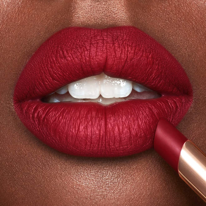 Lips close-up of a deep-tone model wearing cherry ruby red lipstick with a matte finish.