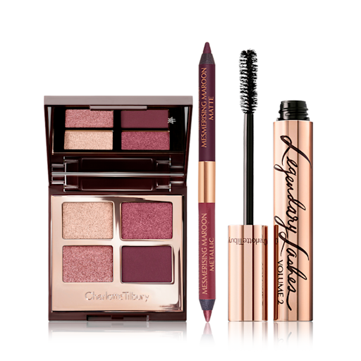 Mesmerising Maroon Magic Trick Eye Kit open An open, quad eyeshadow with a mirrored lid and eyeshadows in shades of purple and golden with a double-sided eyeliner in shades of maroon, and a black mascara with its applicator next to it.