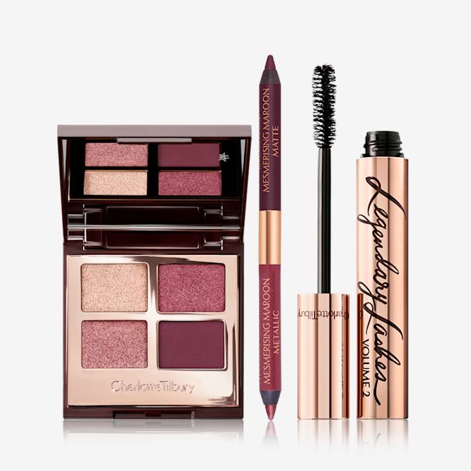 Mesmerising Maroon Magic Trick Eye Kit open An open, quad eyeshadow with a mirrored lid and eyeshadows in shades of purple and golden with a double-sided eyeliner in shades of maroon, and a black mascara with its applicator next to it.