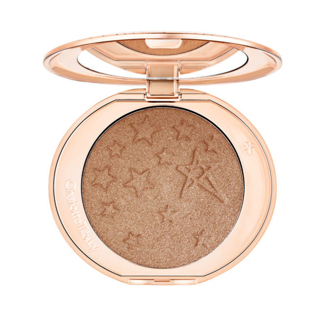 An open highlighter powder compact with a mirrored lid, in a shimmery bronze-gold shade. 