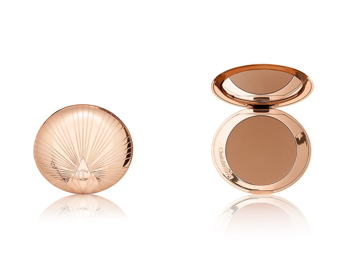 Airbrush Bronzer close and open Two, mirrored-lid bronzers, one open and the other close, in a medium-brown shade in golden-coloured compacts with a starburst pattern on the lid.